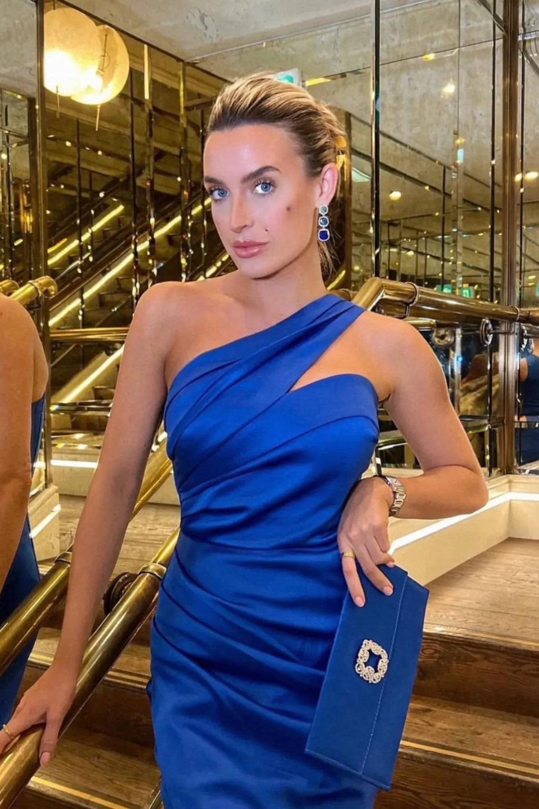 Blue and gold drop earrings on model’s ear, three-stone faceted design