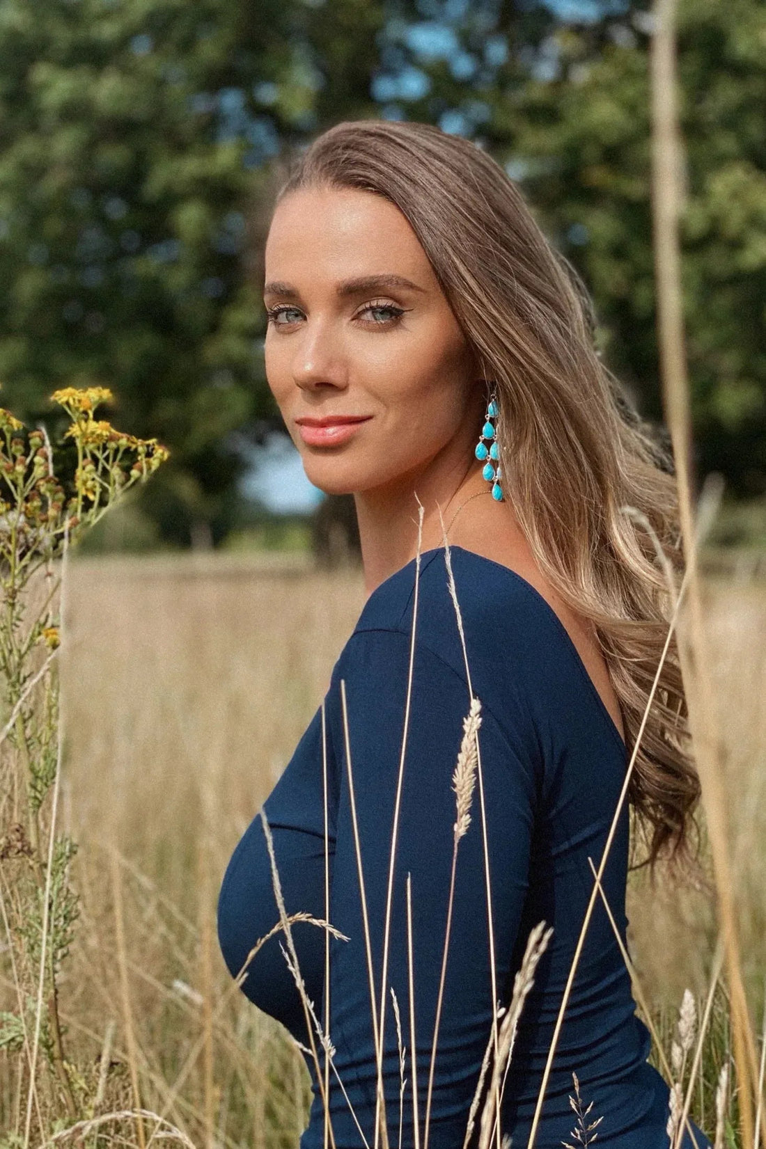 Turquoise teardrop earrings with long silver cascade, worn with blue top
