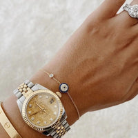 Gold evil eye bracelet on wrist with round blue eye charm