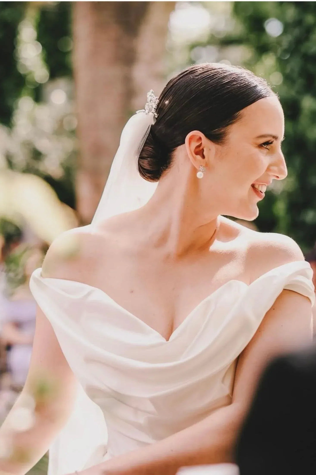 Silver flower-and-pearl stud earrings on a bride’s ear