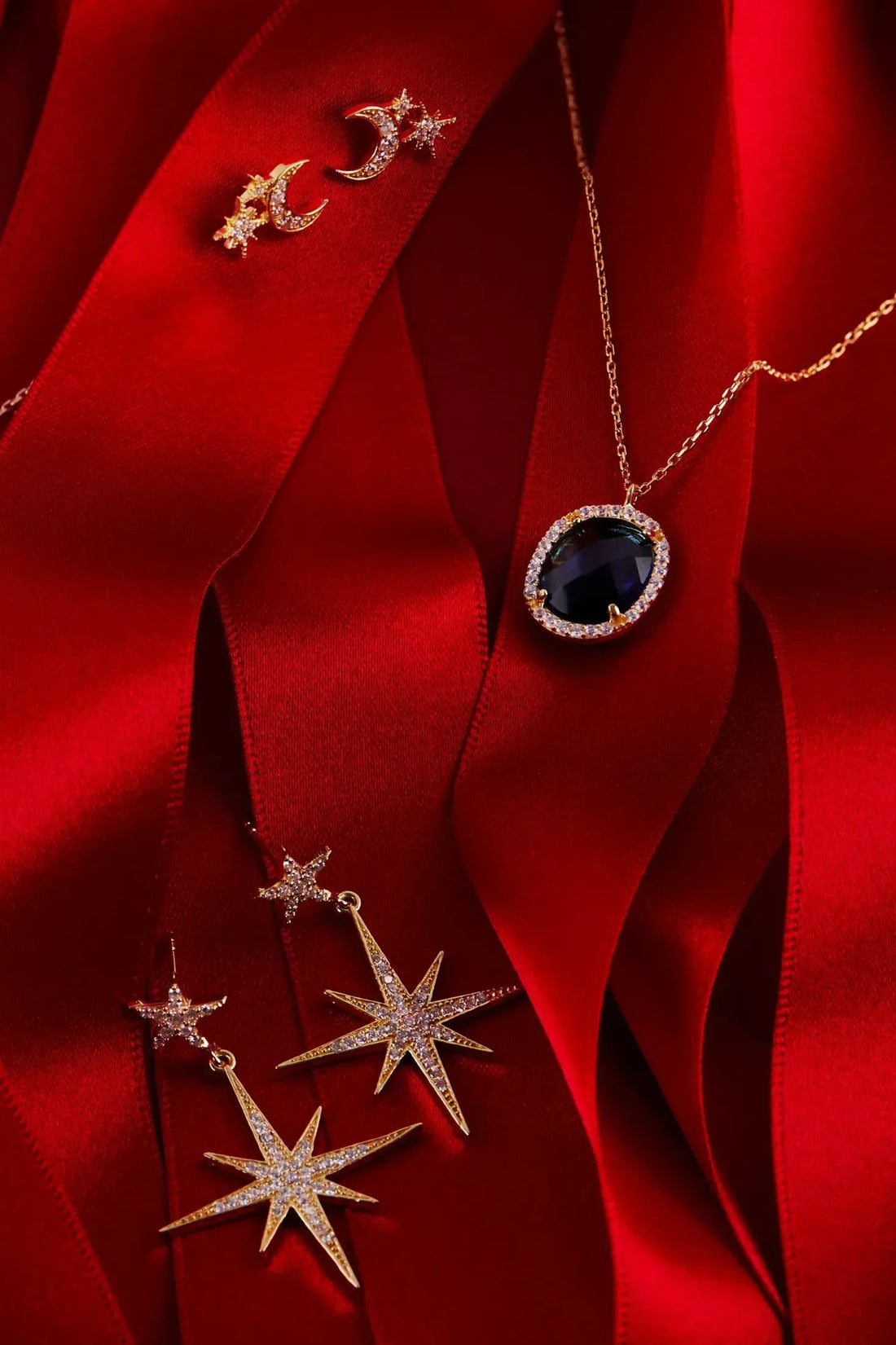 Gold-toned starburst drop earrings with crescent moon and stone accents