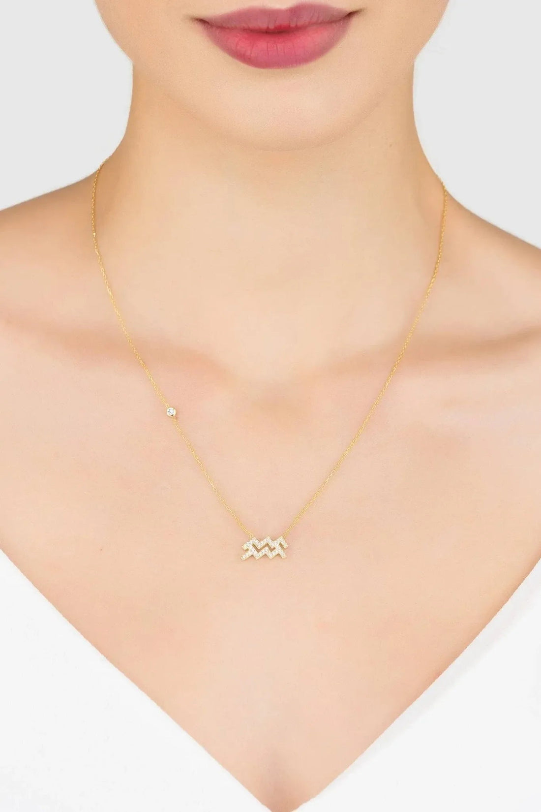 Gold Aquarius star sign pendant necklace on neckline with zigzag crystal charm