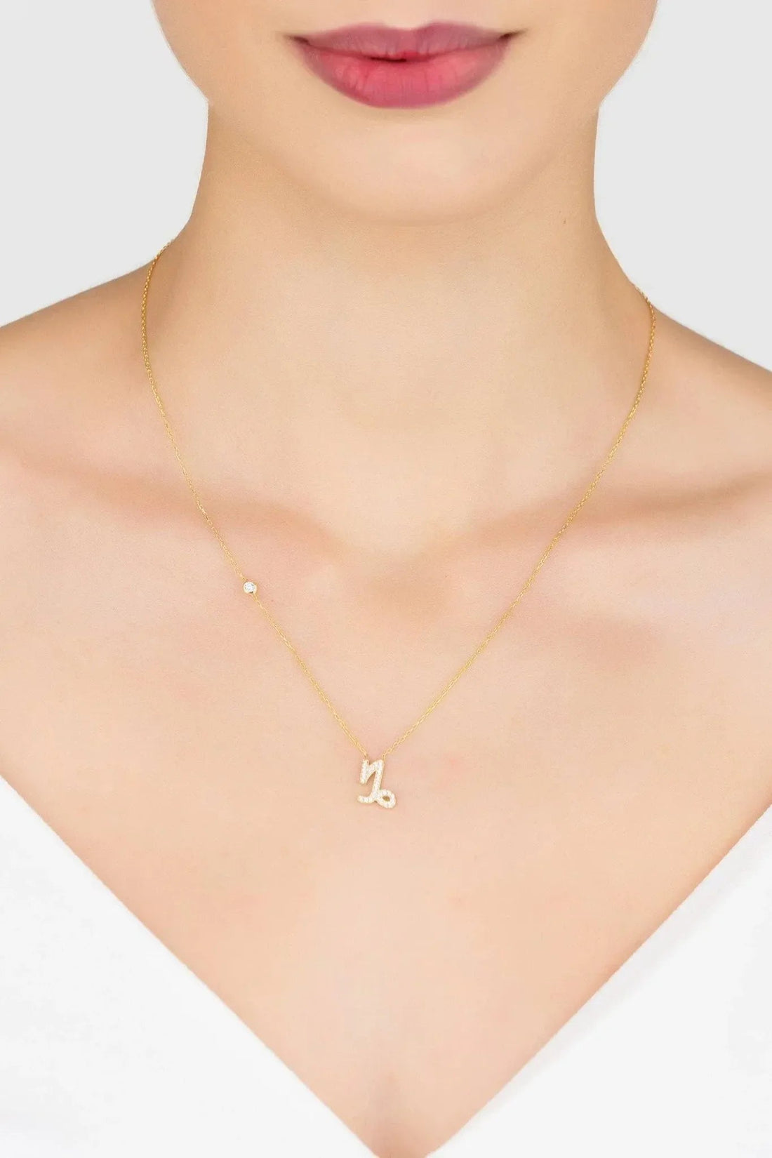 Gold zodiac pendant necklace with small Capricorn charm, worn