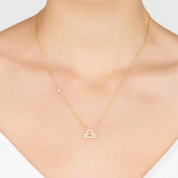 Gold Libra scale pendant necklace worn at the neckline