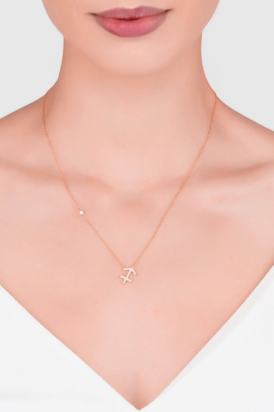 Rose gold zodiac pendant necklace with Sagittarius symbol charm, close-up