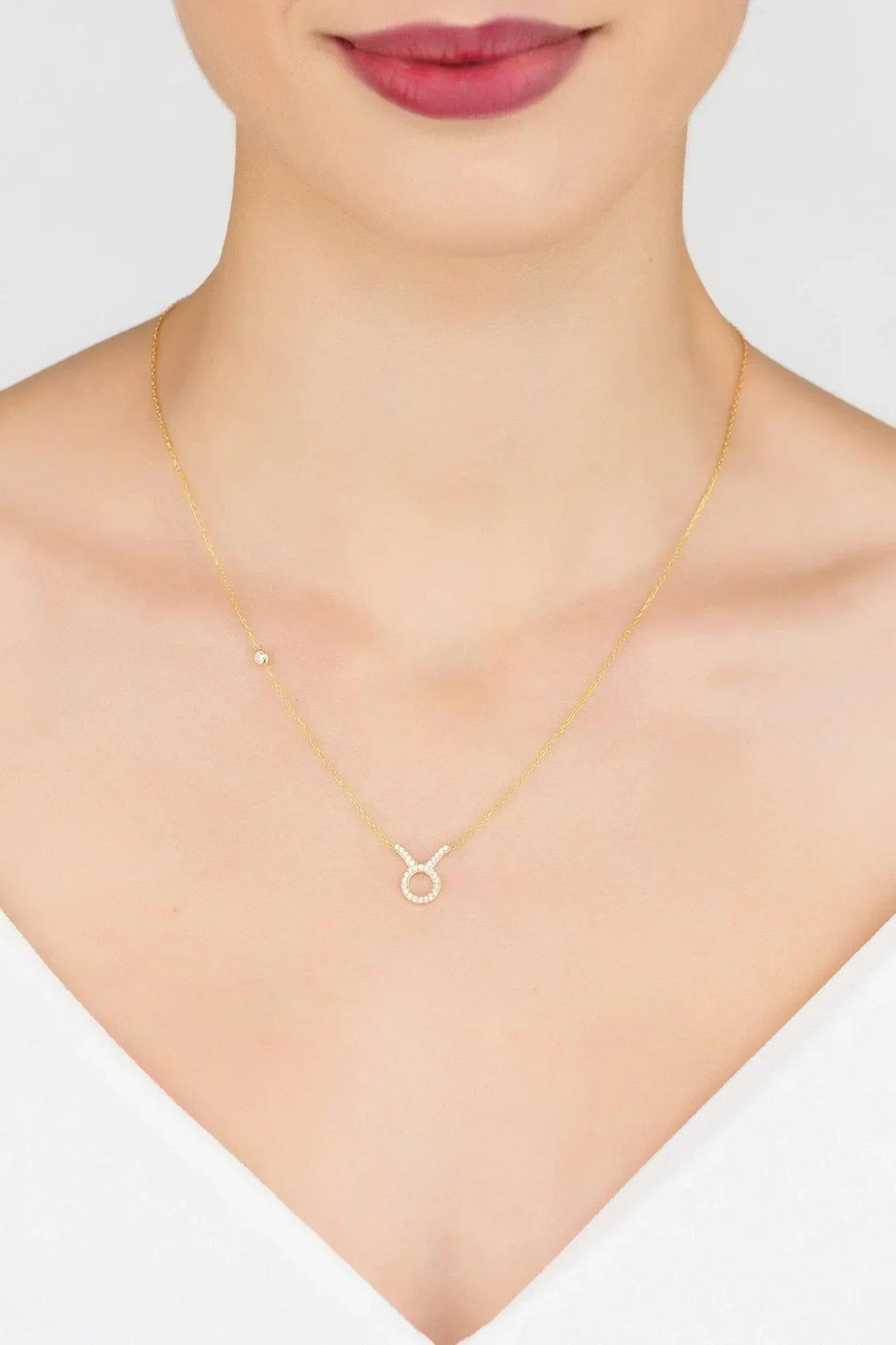 Gold-tone zodiac pendant necklace on model, Taurus symbol with stone border