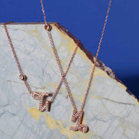 Rose gold Capricorn charm pendant necklace on stone, multiple chains visible