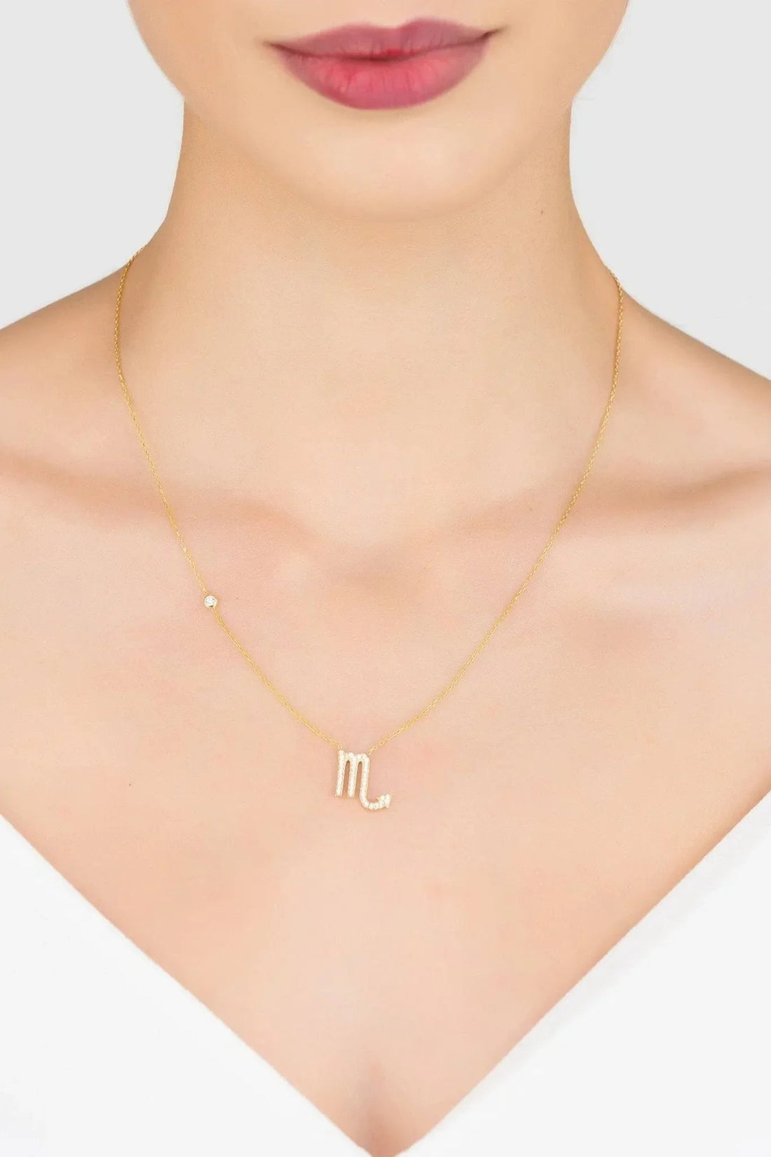 Rose gold Scorpio M zodiac pendant necklace worn at the neckline
