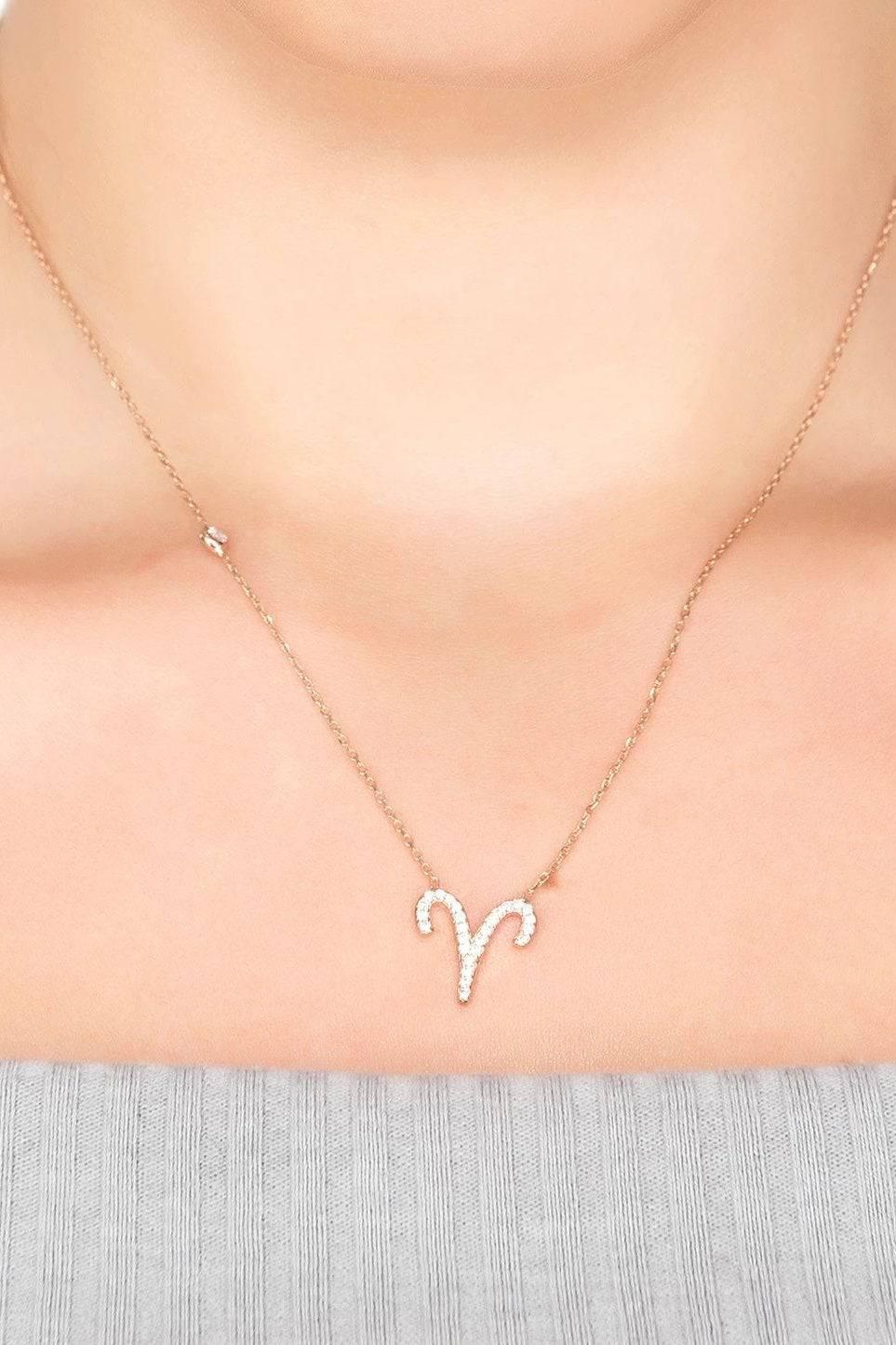 Gold-tone Aries zodiac pendant necklace with rhinestone details on a fine chain